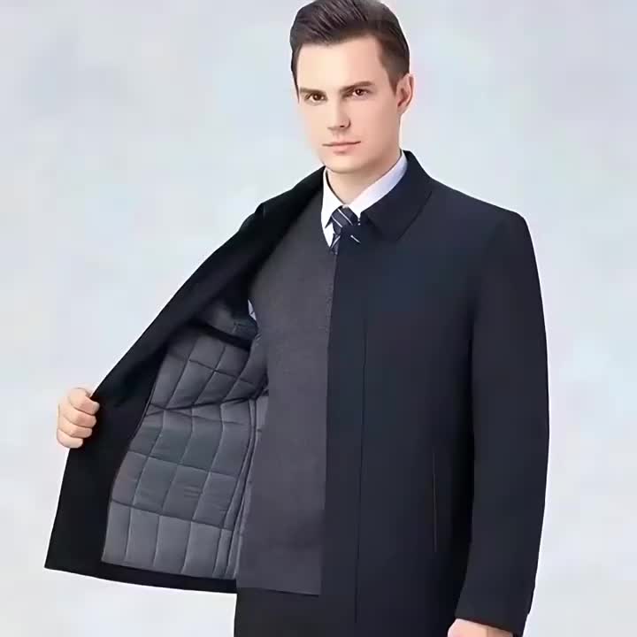 Volledig figuur van de man in de zwarte jas, staand in een ontspannen pose.