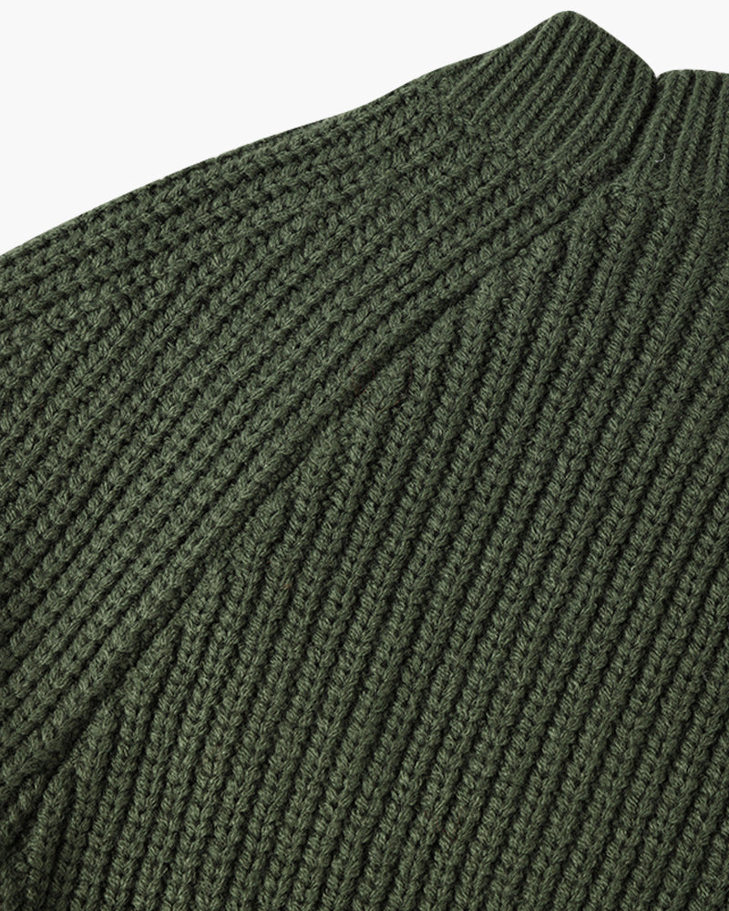 Een man draagt de groene sweater in een lichte omgeving, de stof voelt zacht en warm aan.