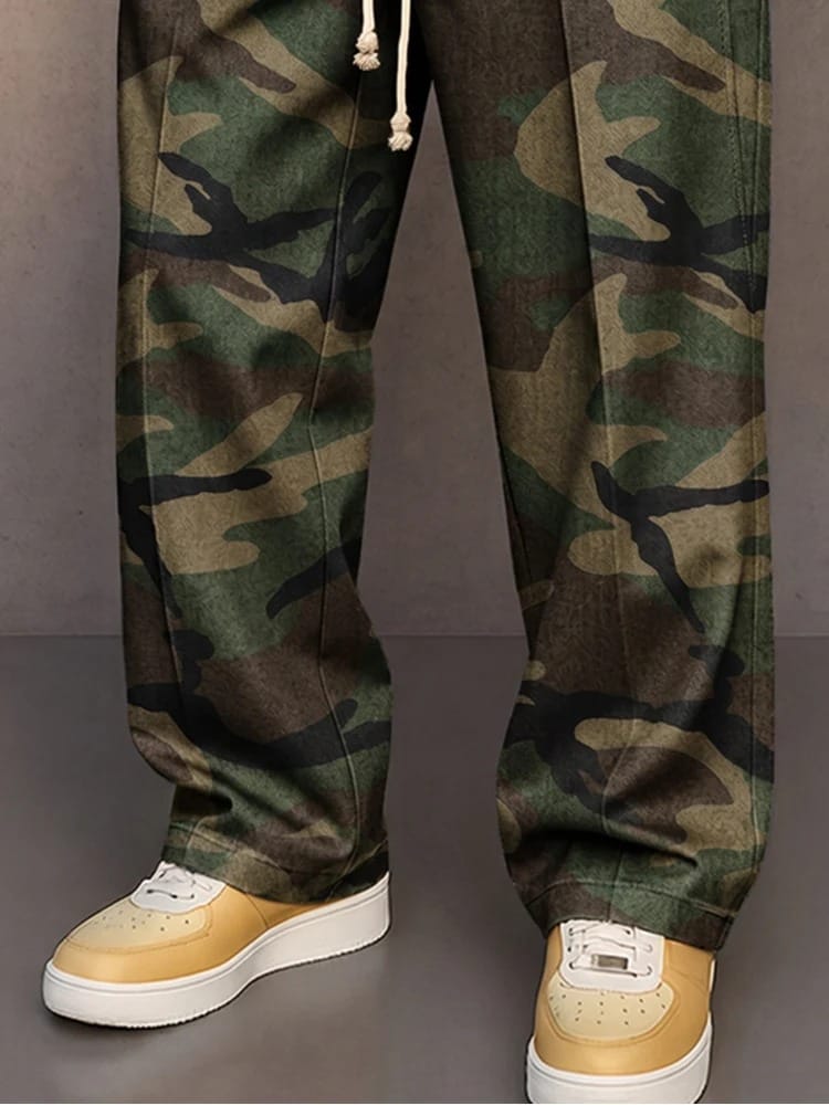 Een man zit ontspannen in de comfortabele camouflage broek, wat de bewegingsvrijheid en het gemak van het kledingstuk benadrukt.