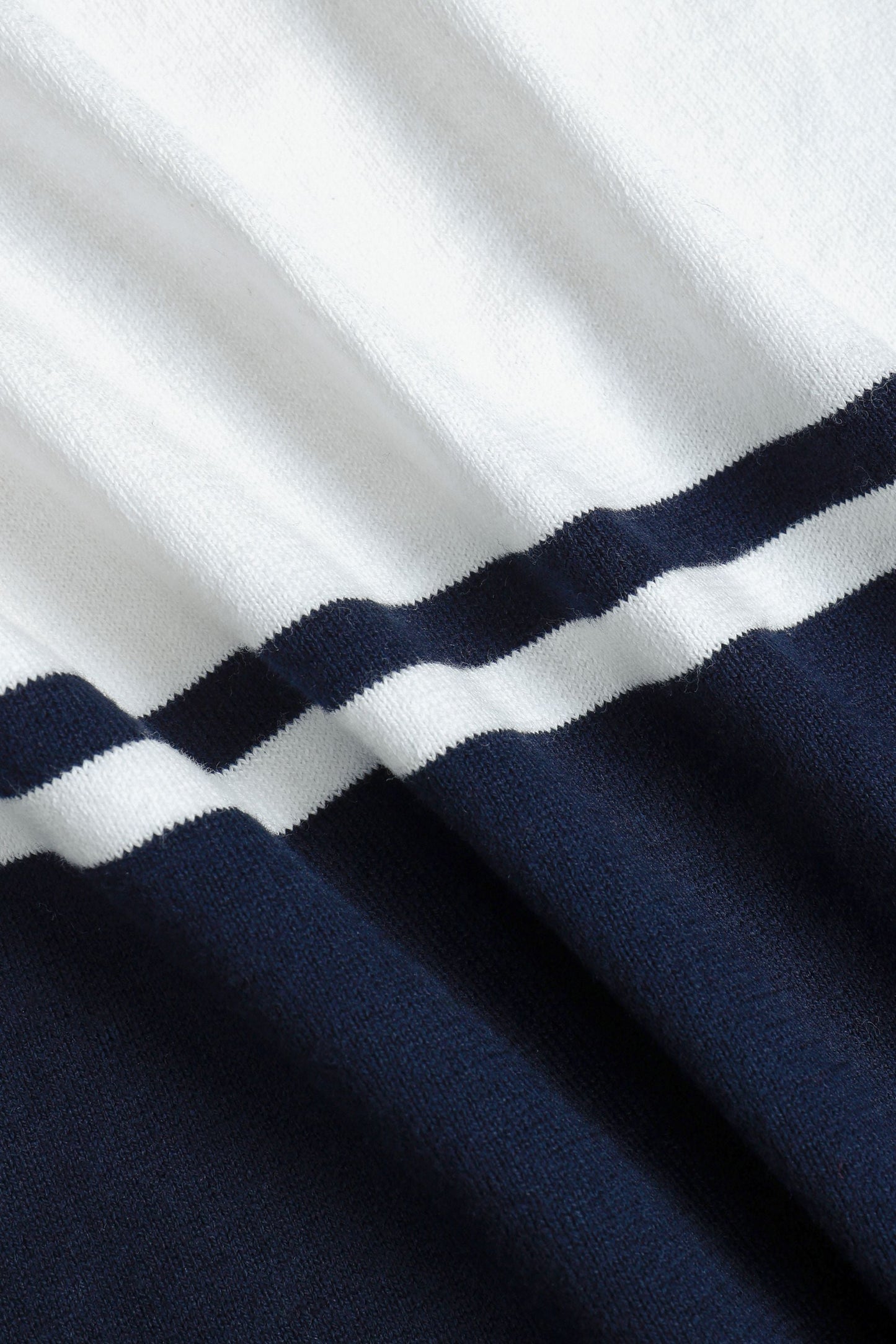 Detailopname van de korte mouw en de afwerking van het gebreide poloshirt, toont de kwaliteit.