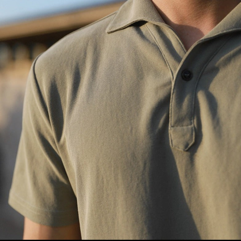 Een man gekleed in het Reuben heren poloshirt, staand in een ontspannen setting, toont de reguliere pasvorm.