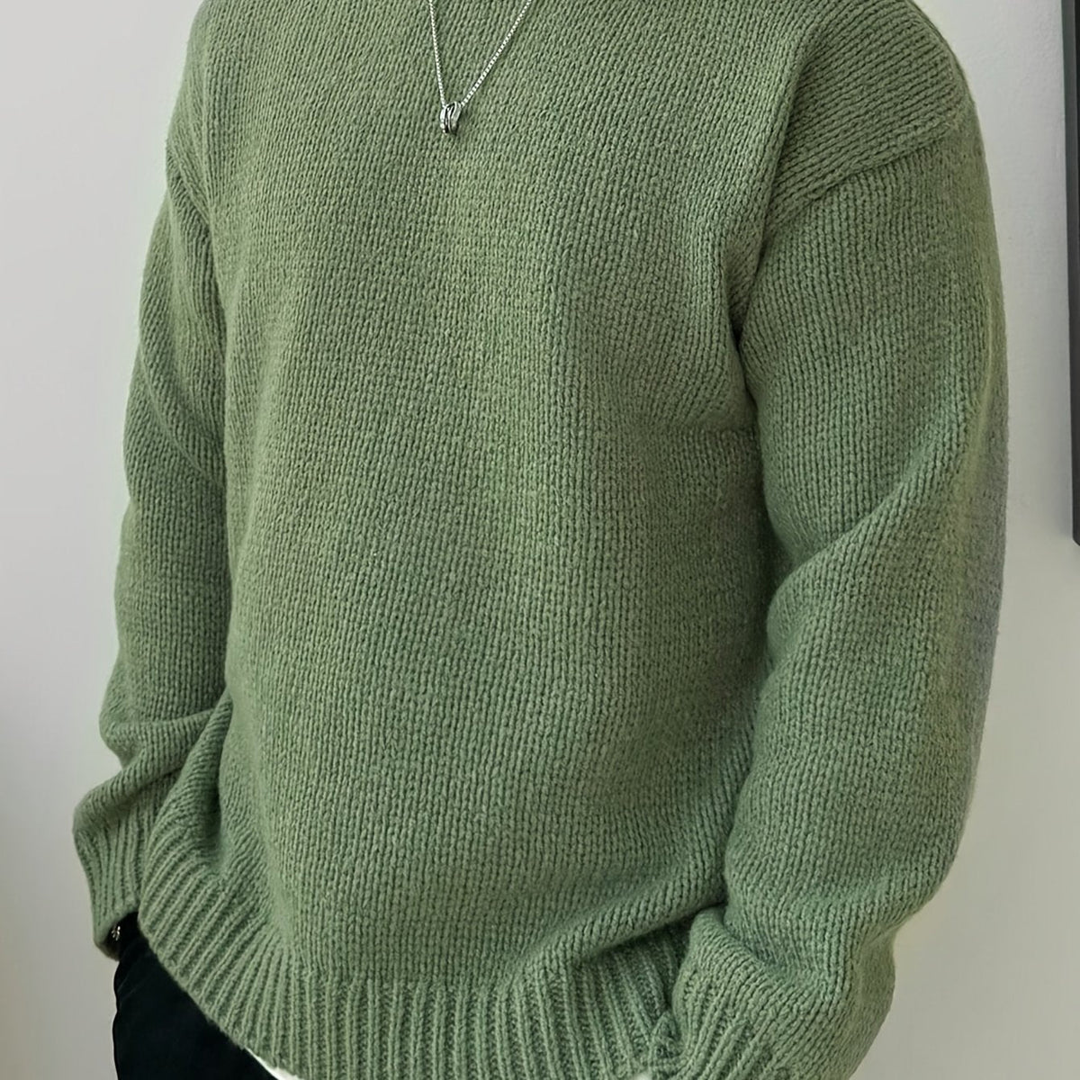 Man in een informele kantooromgeving, draagt de zwarte heren trui over een kraagshirt voor een smart-casual uitstraling.