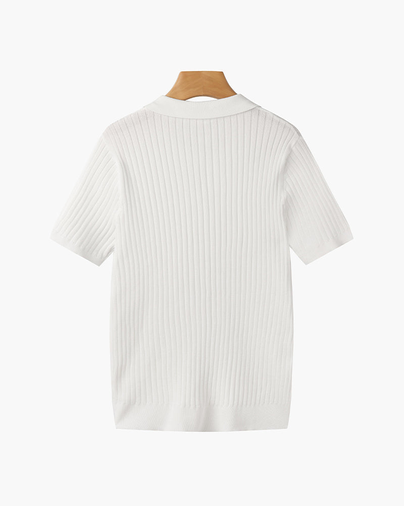 Model draagt het witte V-hals poloshirt, staand in een ontspannen houding en volledige look.