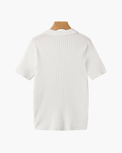 Model draagt het witte V-hals poloshirt, staand in een ontspannen houding en volledige look.