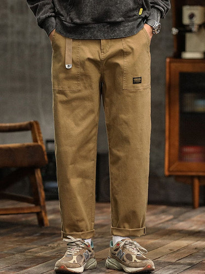 Detailopname van de knoop- en ritssluiting van de zwarte katoenen twill broek, met de textuur van de stof.