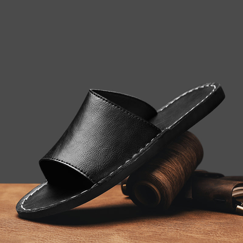 De zwarte leren sandalen van voren gezien, met de gestroomlijnde cross-wrap pasvorm duidelijk zichtbaar.