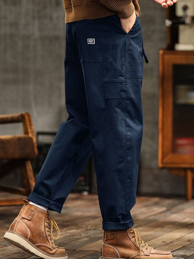 Gedragen detail van de marineblauwe broek, met subtiele plooien die het zachte twill karakter benadrukken.