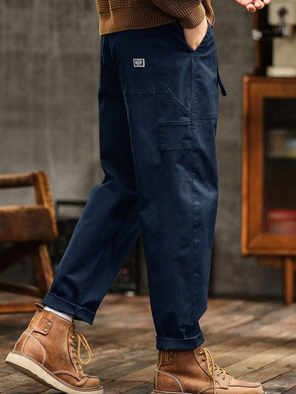 Gedragen detail van de marineblauwe broek, met subtiele plooien die het zachte twill karakter benadrukken.