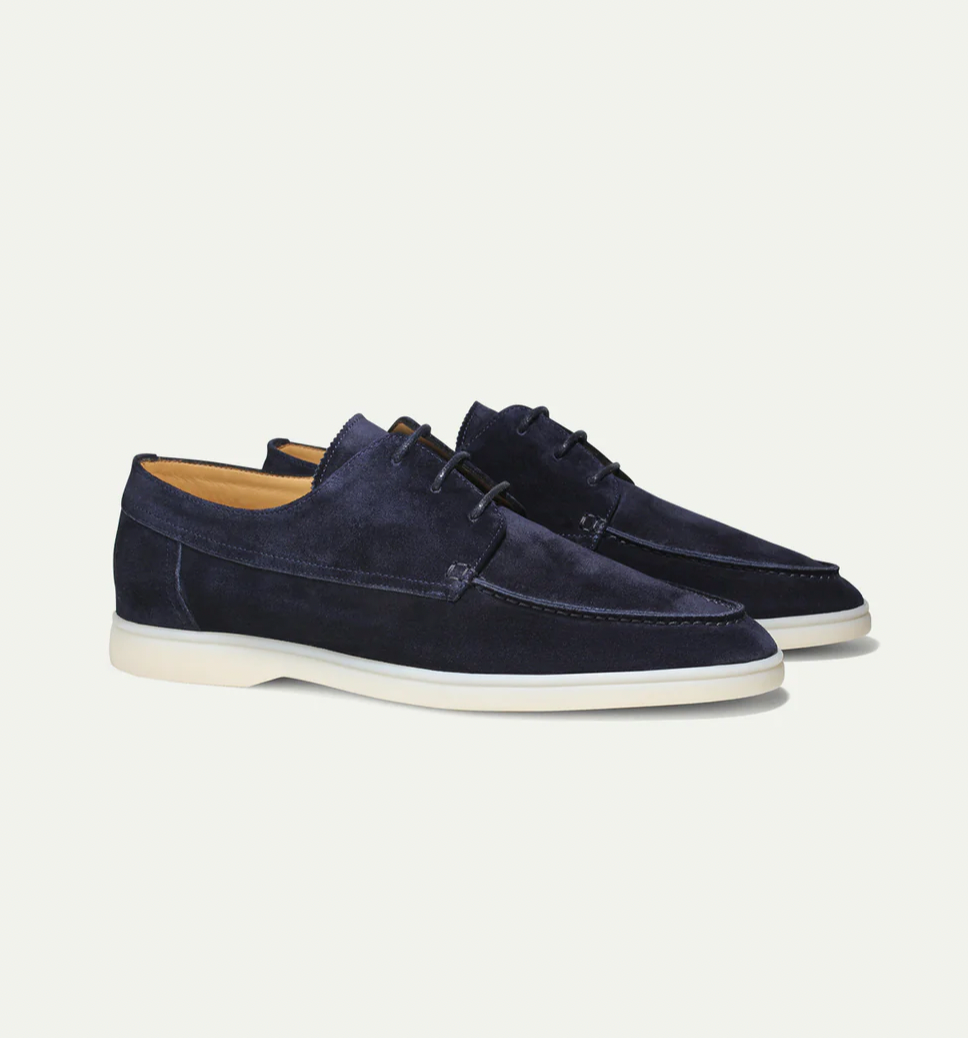 Detailopname van de textuur van het hoogwaardige suède van de heren loafers, met fijne stiksels zichtbaar.