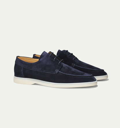 Detailopname van de textuur van het hoogwaardige suède van de heren loafers, met fijne stiksels zichtbaar.