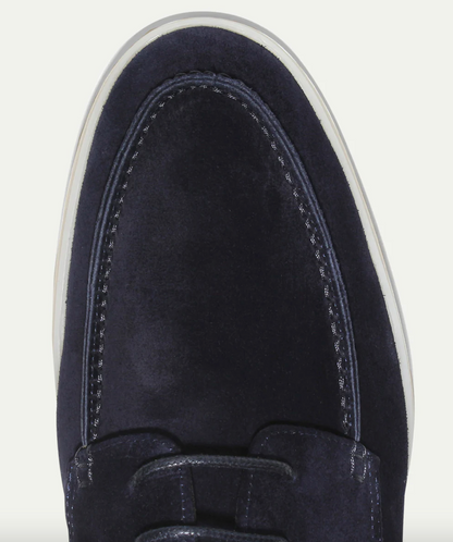 Een man die de stijlvolle suède loafers draagt in combinatie met een nette broek en blazer, perfect voor formele gelegenheden.
