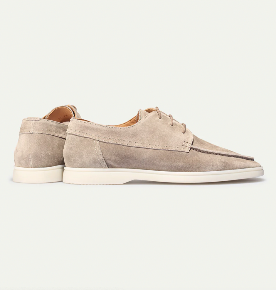 De suède instapschoenen gedragen in een casual setting, gecombineerd met een linnen broek en polo, voor een ontspannen look.