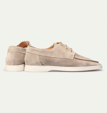 De suède instapschoenen gedragen in een casual setting, gecombineerd met een linnen broek en polo, voor een ontspannen look.