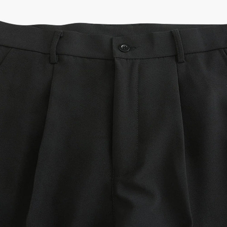 Detailopname van de traditionele knoopsluiting en de hoogwaardige riemlussen op de zwarte pantalon.