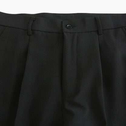 Detailopname van de traditionele knoopsluiting en de hoogwaardige riemlussen op de zwarte pantalon.