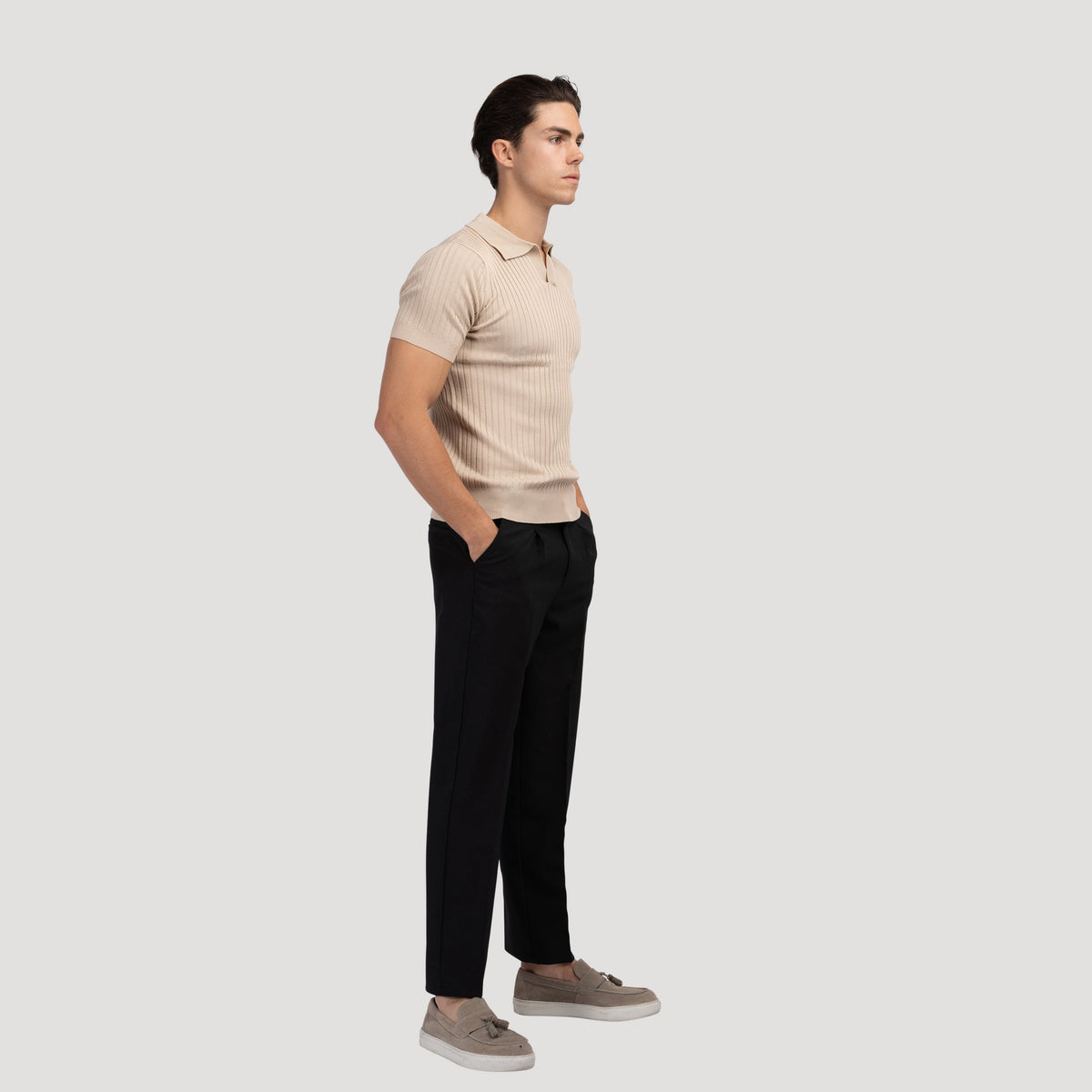 Model in het beige V-hals poloshirt, zittend op een bank, ontspannen en comfortabel in het shirt.