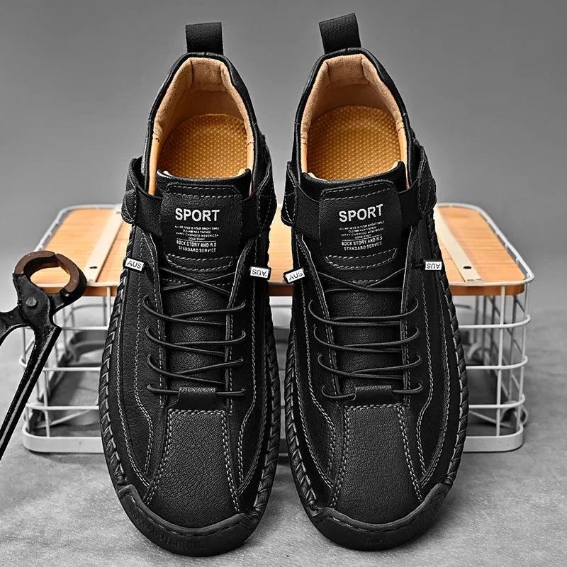 De zwarte leren herensneakers op een houten vloer, voor een klassieke presentatie.