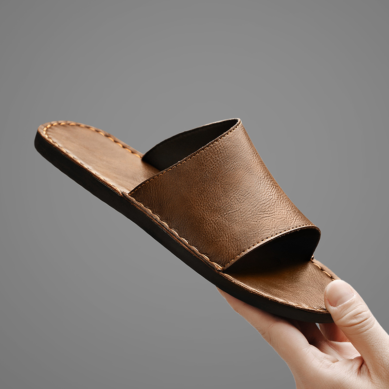 Close-up van de handgestikte contrasterende stiksels op de leren sandalen, met focus op de kwaliteit.