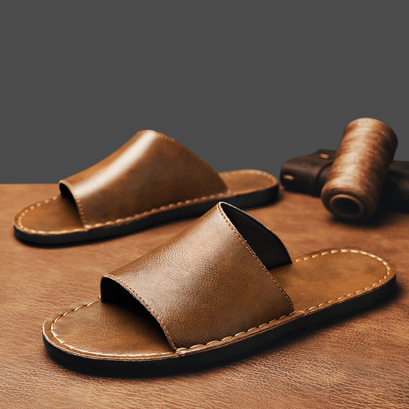 Zijaanzicht van de bruine leren sandalen, tonend de gedempte platte zool en de handgestikte afwerking.
