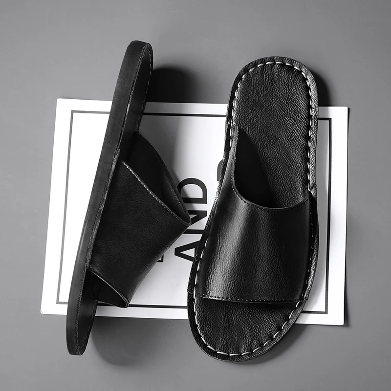 Een paar zwarte leren sandalen gepresenteerd in een minimalistische studio-omgeving.