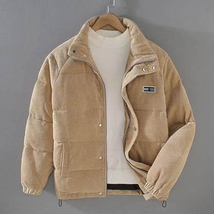 Zijaanzicht van de warme corduroy jas in elegant grijs, met detail van de opstaande kraag en de twee voorzakken.