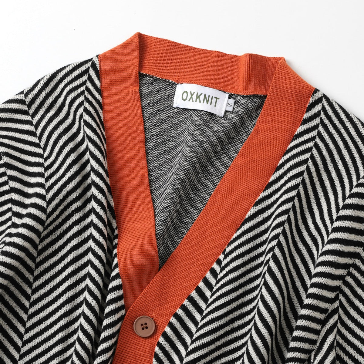 Man draagt de zwarte cardigan in een ontspannen, stedelijke setting, gecombineerd met een casual outfit, voor een streetwear look.