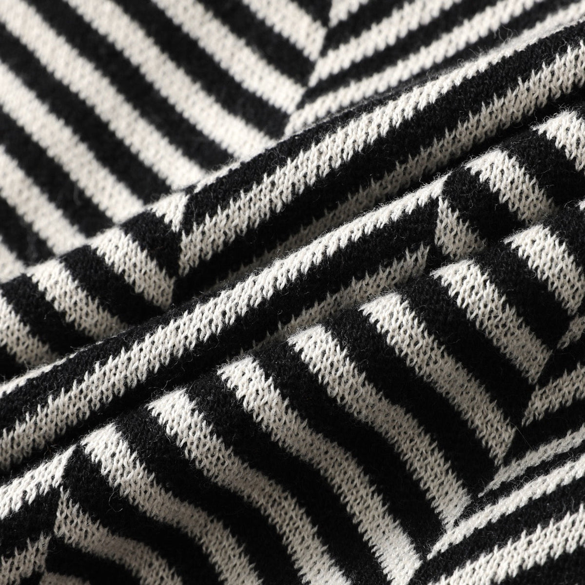 Zijaanzicht van de zwarte gebreide cardigan, gedragen door een man, benadrukt de lengte en de mouwdetails van het kledingstuk.