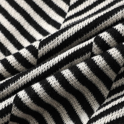 Zijaanzicht van de zwarte gebreide cardigan, gedragen door een man, benadrukt de lengte en de mouwdetails van het kledingstuk.