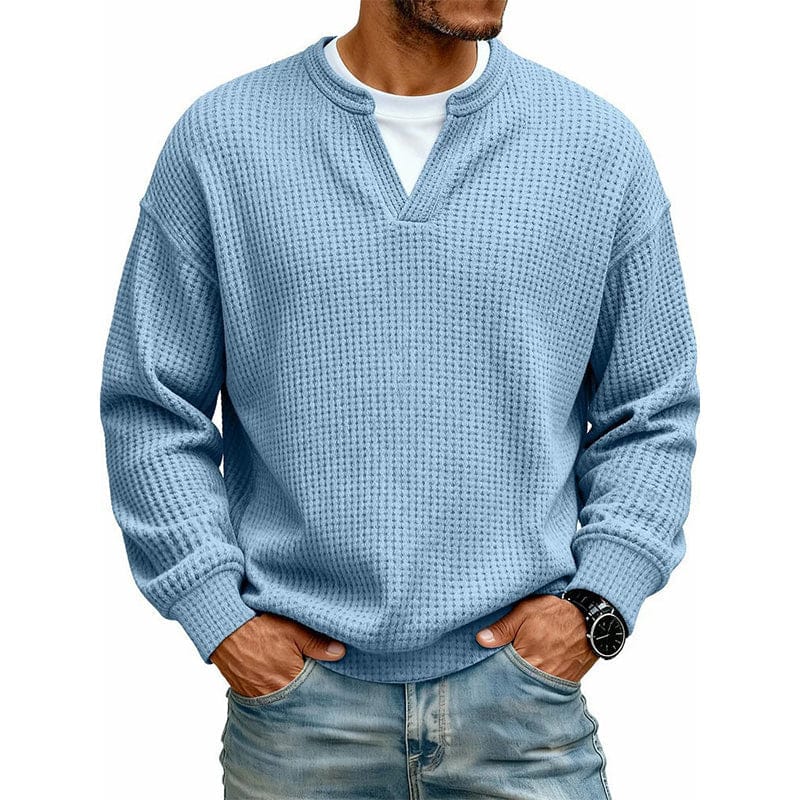 Een man toont de veelzijdigheid van de Merijn wafelgebreide trui in marineblauw, gecombineerd met een overhemd.