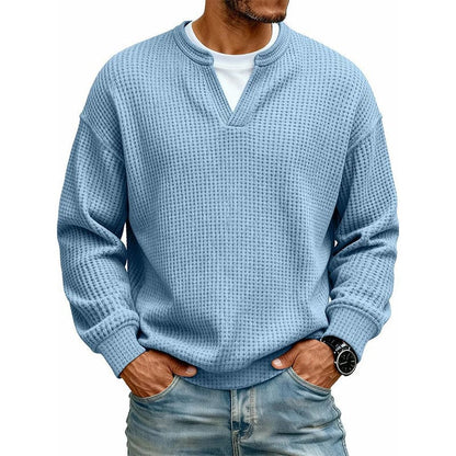 Een man toont de veelzijdigheid van de Merijn wafelgebreide trui in marineblauw, gecombineerd met een overhemd.