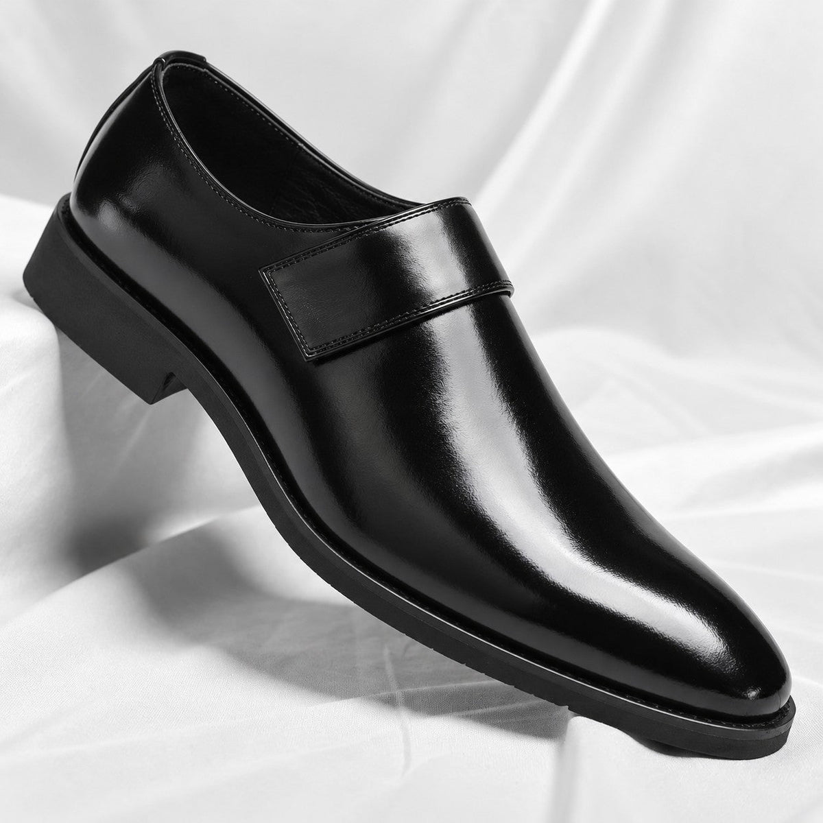 Een man stapt in de zwarte leren loafers, wat het gemak van het instapmodel illustreert.