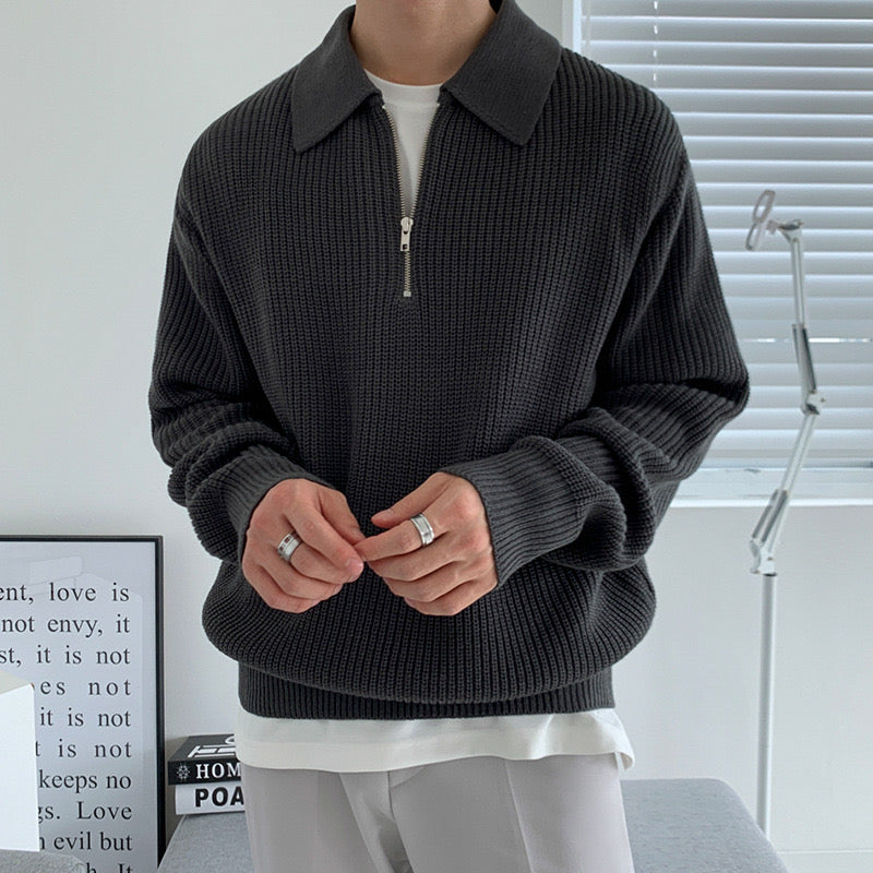 De half-zip trui gedragen met een wit T-shirt eronder, wat de veelzijdigheid van de outfit benadrukt.