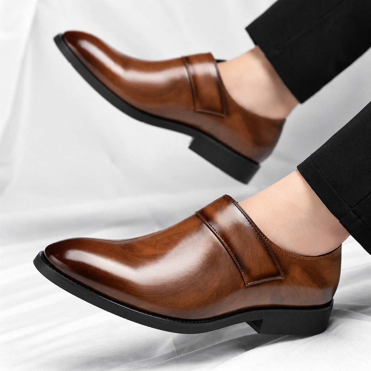 Een man draagt de bruine leren loafers in een zakelijke setting, gecombineerd met een nette pantalon.