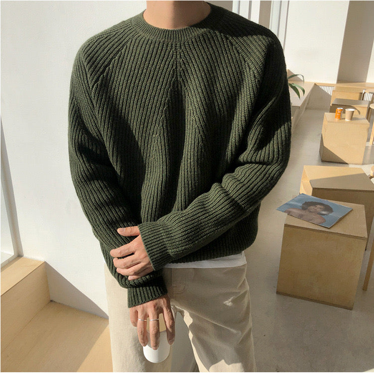 Detailopname van de zachte, dik geribbelde textuur van de groene heren sweater.