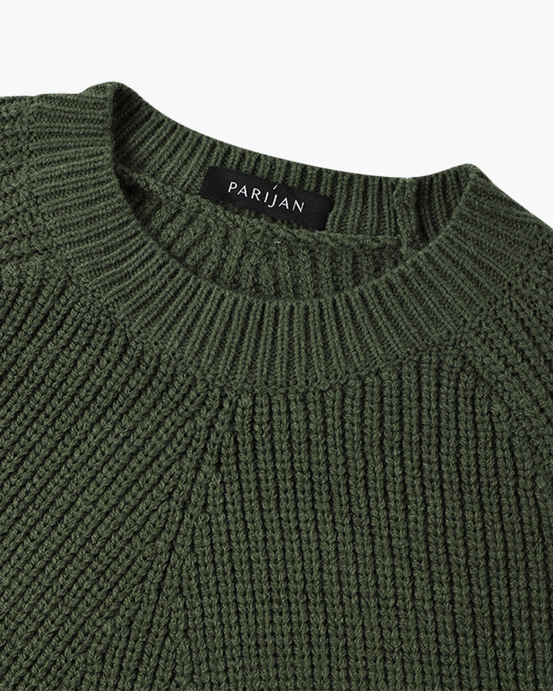 Model toont de veelzijdigheid van de groene sweater, gecombineerd met een donkere broek.