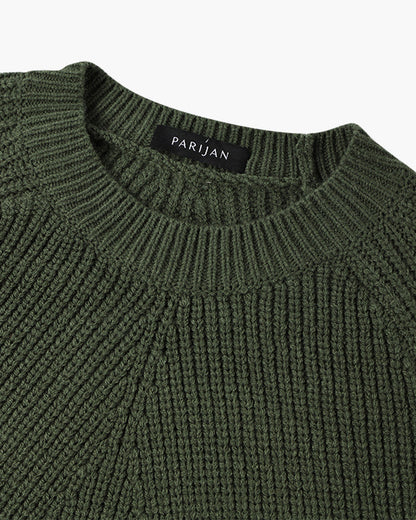 Model toont de veelzijdigheid van de groene sweater, gecombineerd met een donkere broek.