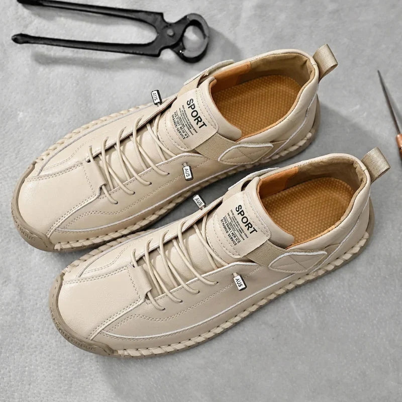 De grijze leren herensneakers op een lichte ondergrond, toont de veelzijdigheid.