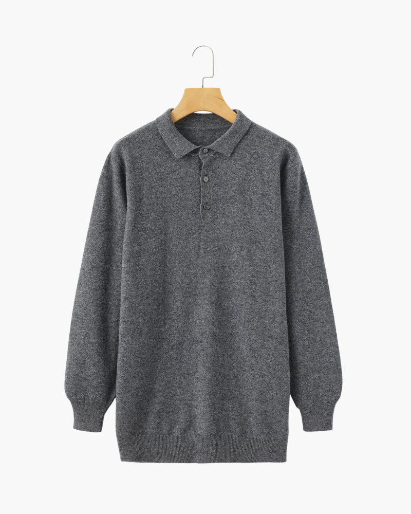 De donkergrijze kasjmier polo sweater gedragen onder een jas, toont de geschiktheid voor gelaagdheid in koudere seizoenen.