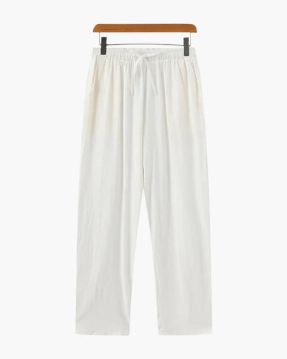 Een man draagt de witte linnen broek, staand in een ontspannen pose, wat de casual elegantie benadrukt.