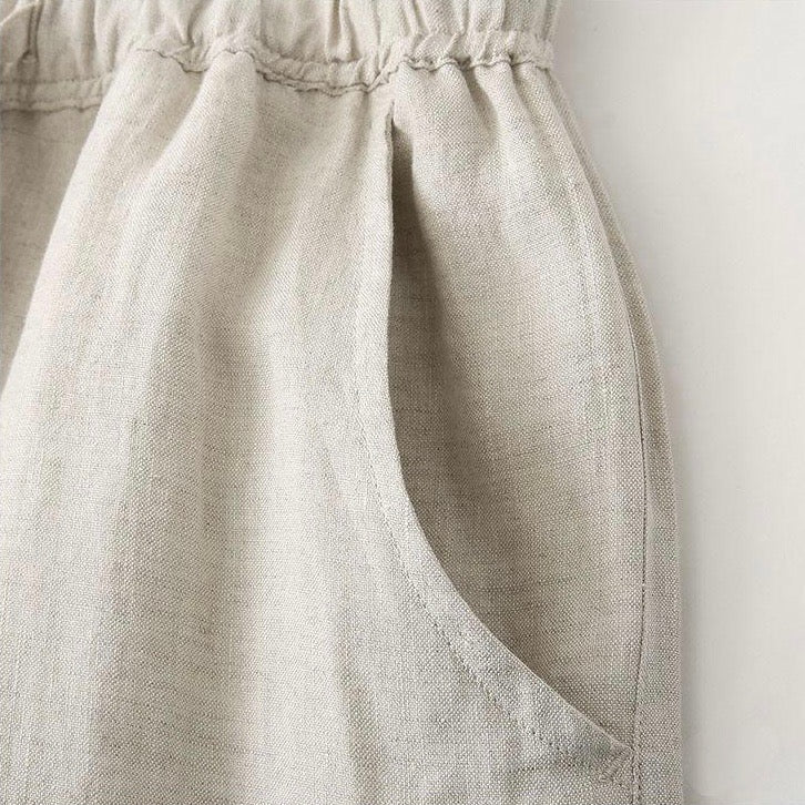 Een man zit relaxed, de linnen broek in beige kleur is prominent, wat het comfort en de ademende stof accentueert.