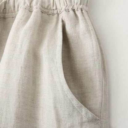 Een man zit relaxed, de linnen broek in beige kleur is prominent, wat het comfort en de ademende stof accentueert.