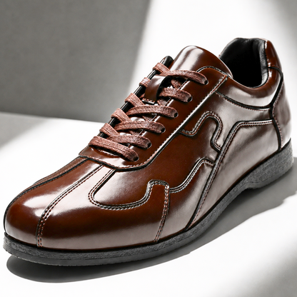 Detailopname van de gestikte panelen op de zijkant van de Silas bruine leren sneakers, met focus op het vakmanschap.