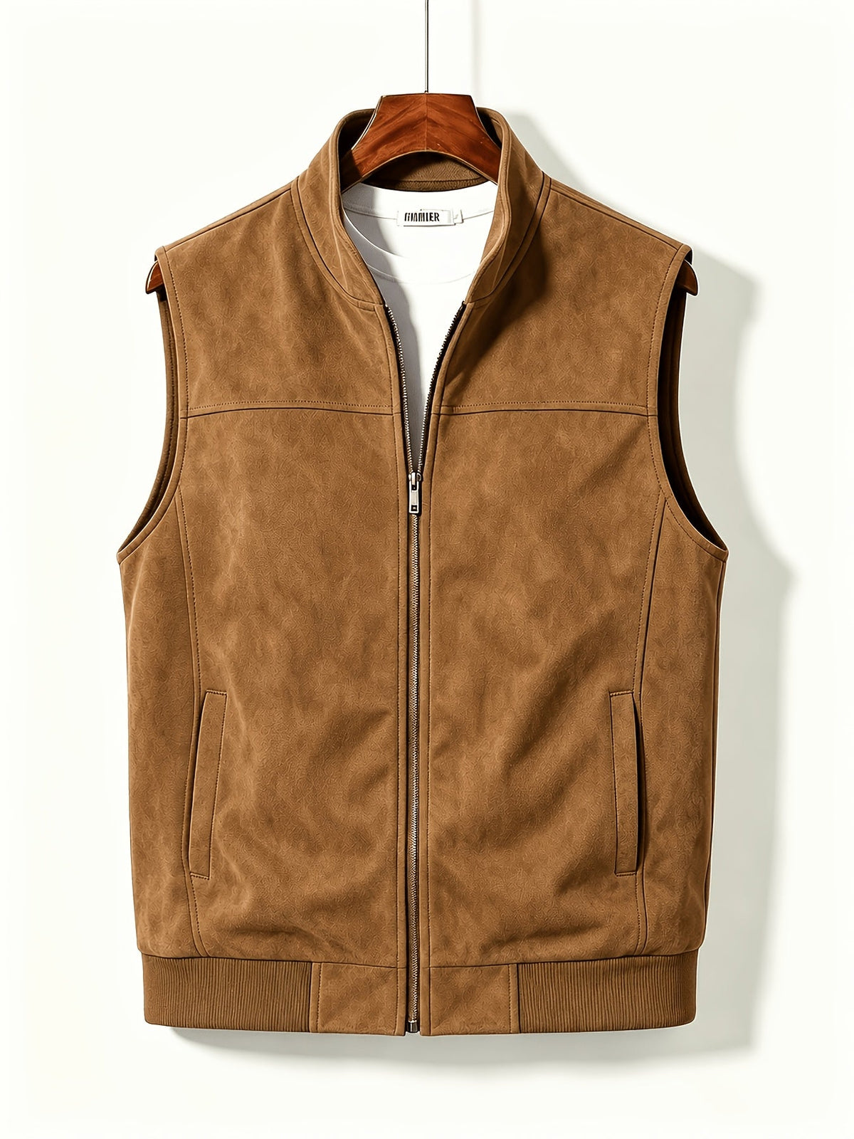 Een man in een zwart mouwloos vest met geribbelde zoom, gecombineerd met een lange mouwen shirt en jeans, in een ontspannen pose.