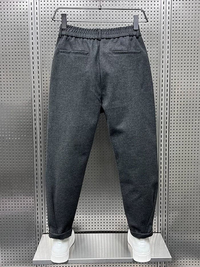 Benen van een model dat de zwarte broek draagt, met focus op de taps toelopende pijpen naar de enkel.