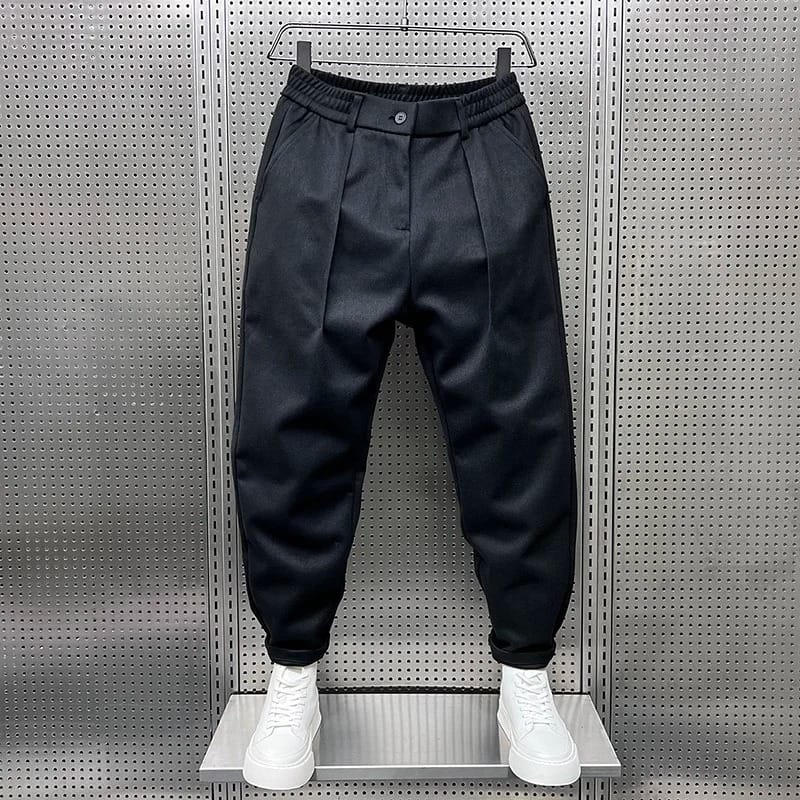 Model draagt de grijze broek in een ontspannen setting, benadrukt de veelzijdigheid en het comfort.