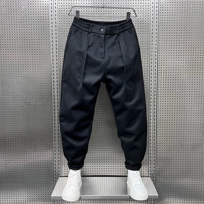 Model draagt de grijze broek in een ontspannen setting, benadrukt de veelzijdigheid en het comfort.