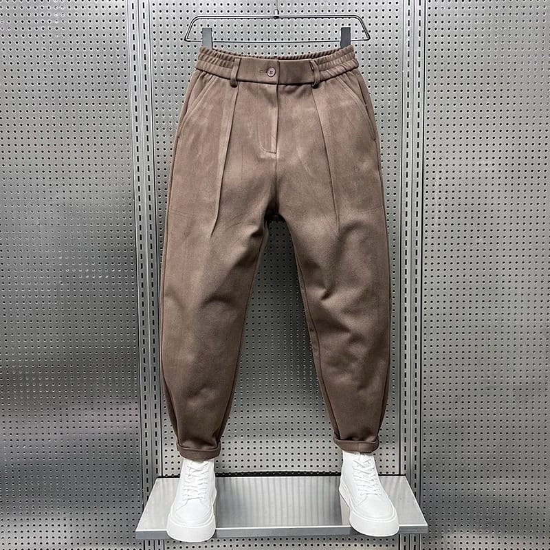 Zijaanzicht van de bruine taps toelopende broek, toont de elegante val van de stof en de pasvorm.
