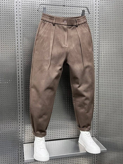 Een stapel van de broeken in verschillende kleuren: bruin, grijs en zwart, mooi opgevouwen.