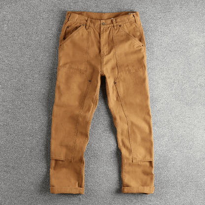 Zijaanzicht van de grijze utility broek, gedragen door een staande man, die de comfortabele pasvorm toont.