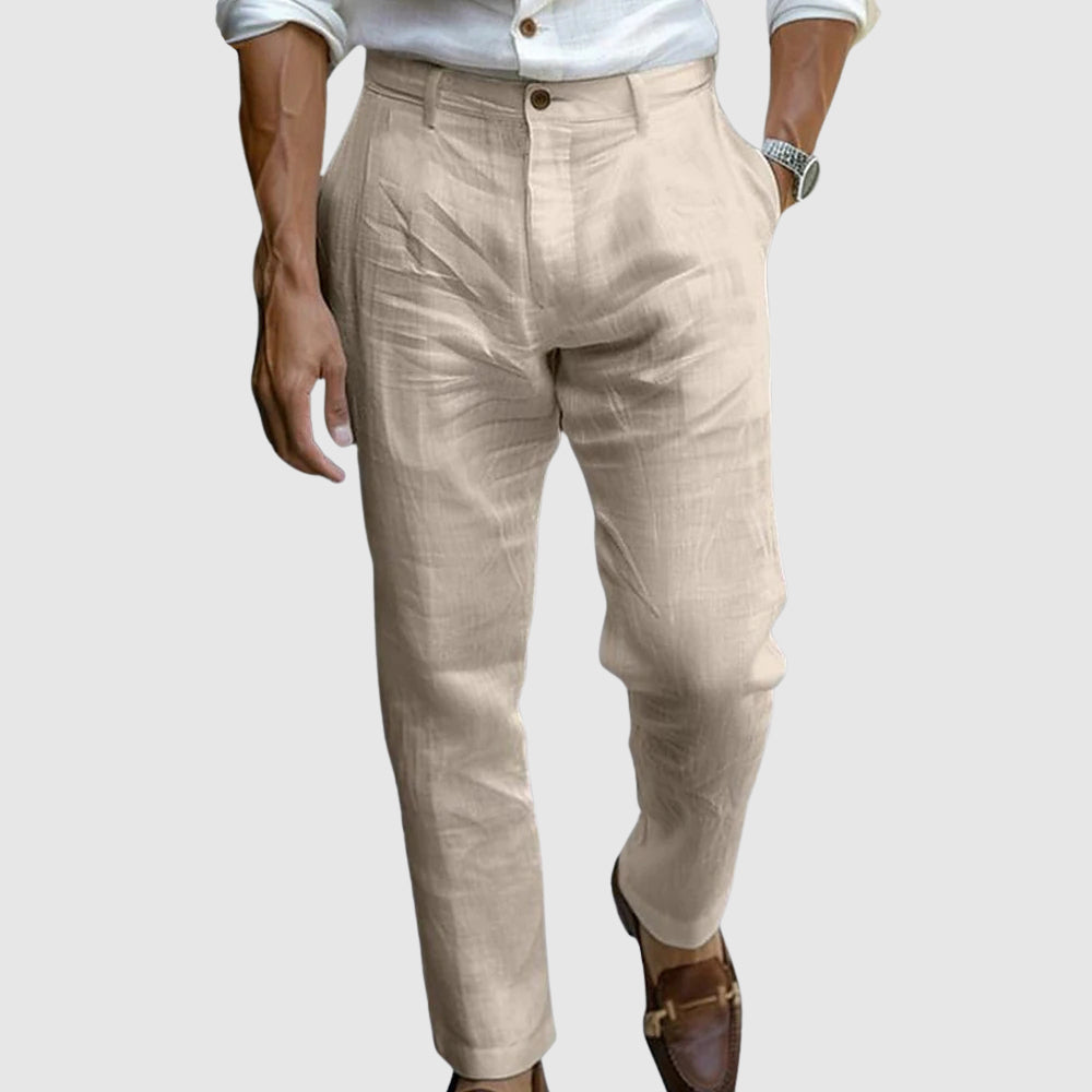 Een man die de kaki linnen broek draagt terwijl hij langs het strand loopt, wat de veelzijdigheid en het comfort benadrukt.